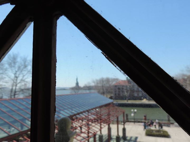 La statue de la Liberté à portée de main, derrière une vitre d'un bâtiment d'Ellis Island