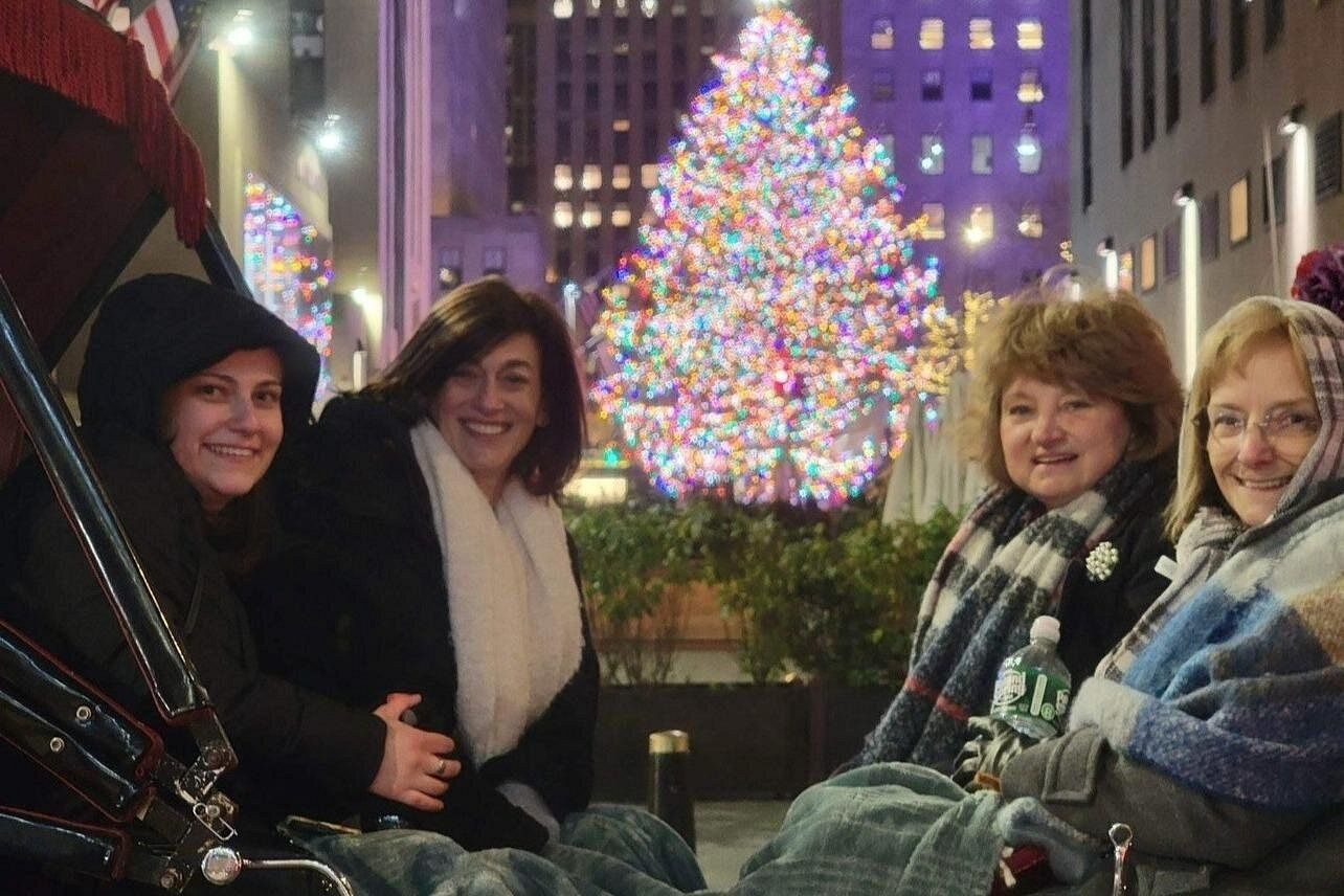 4 femmes dans une calèche avec l'arbre de Noël du Rockefeller Center en fond