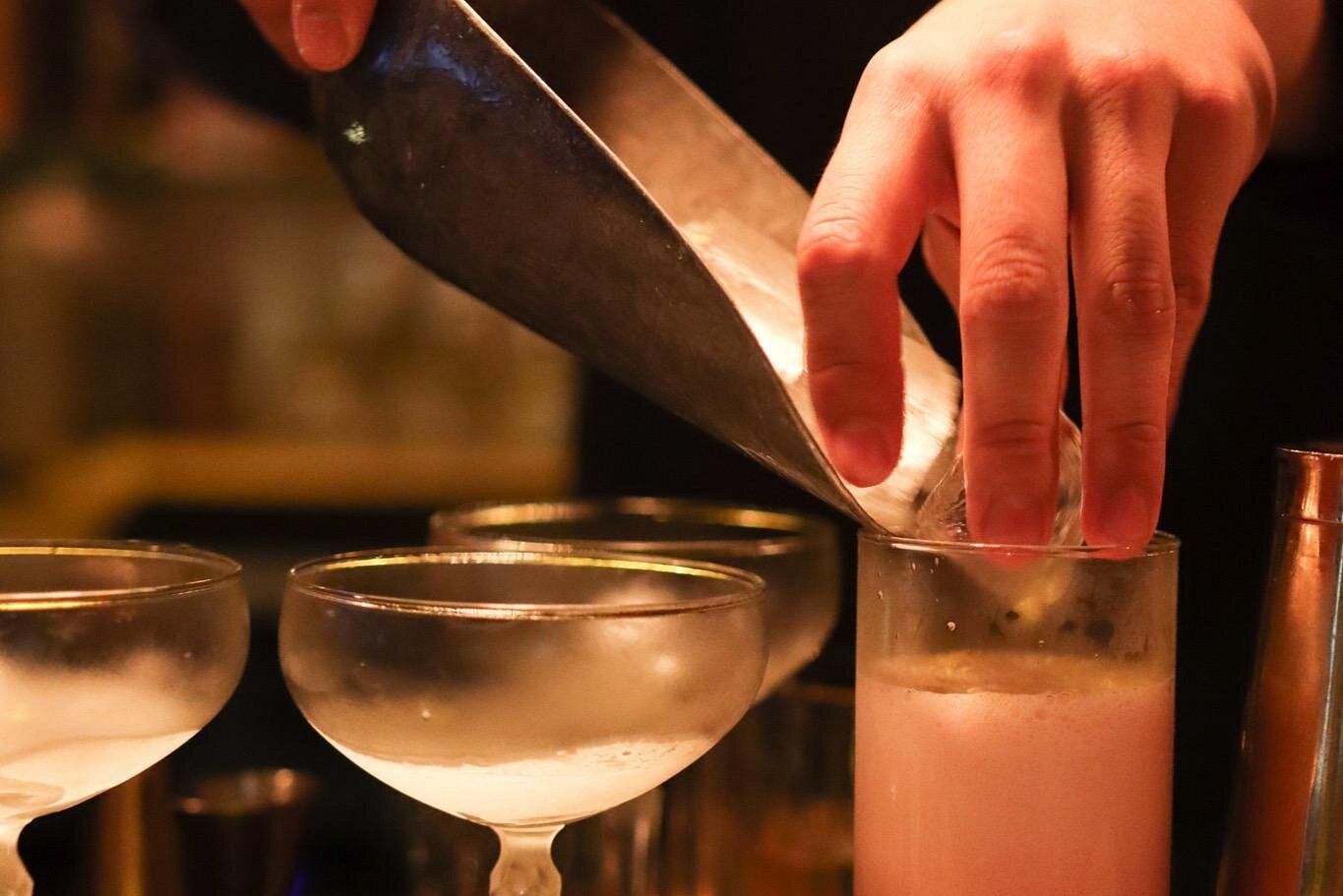 Gros plan sur les mains d'un barman réalisant un cocktail dans un bar à New York