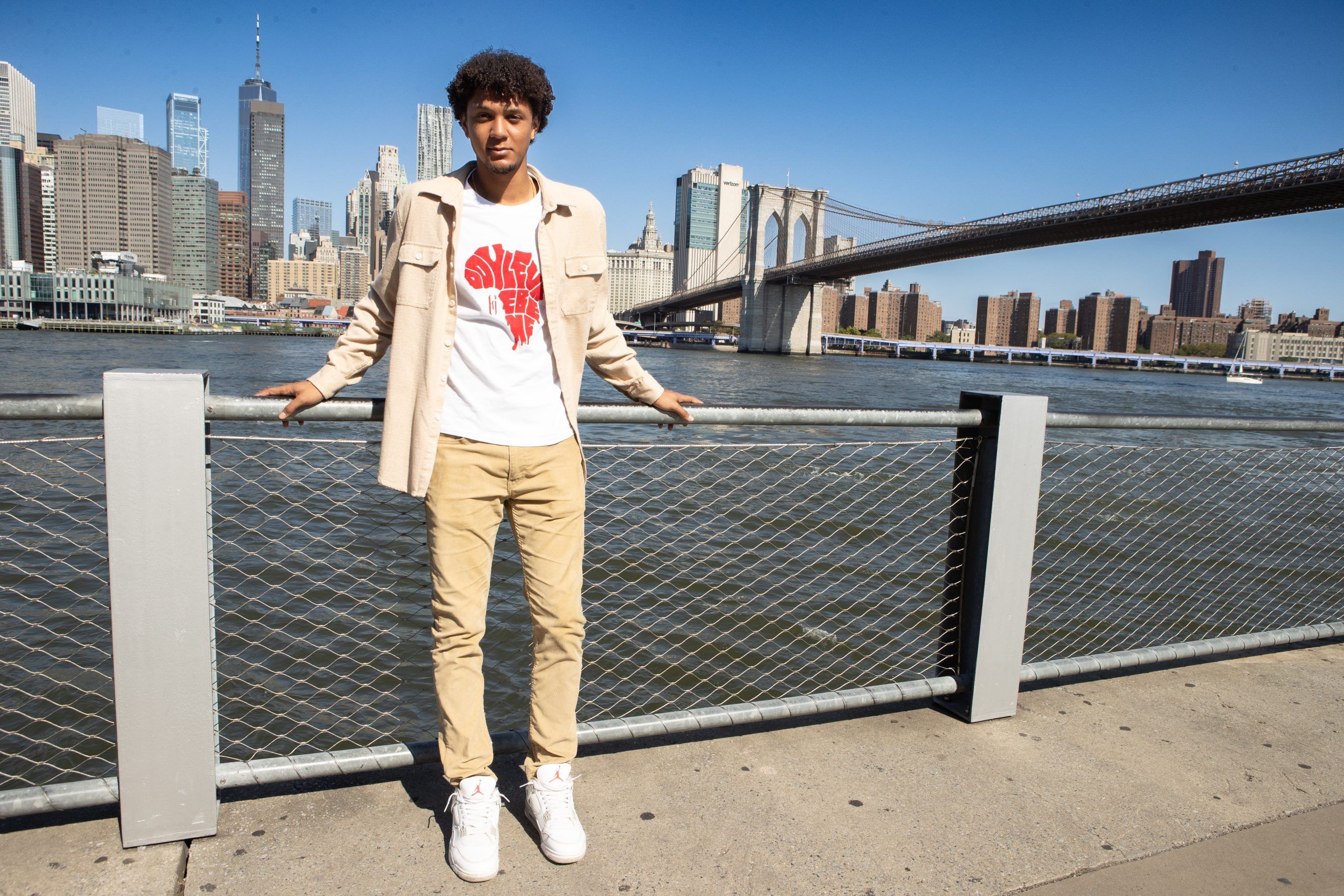 Jeune homme posant devant la skyline de Manhattan et le pont de Brooklyn