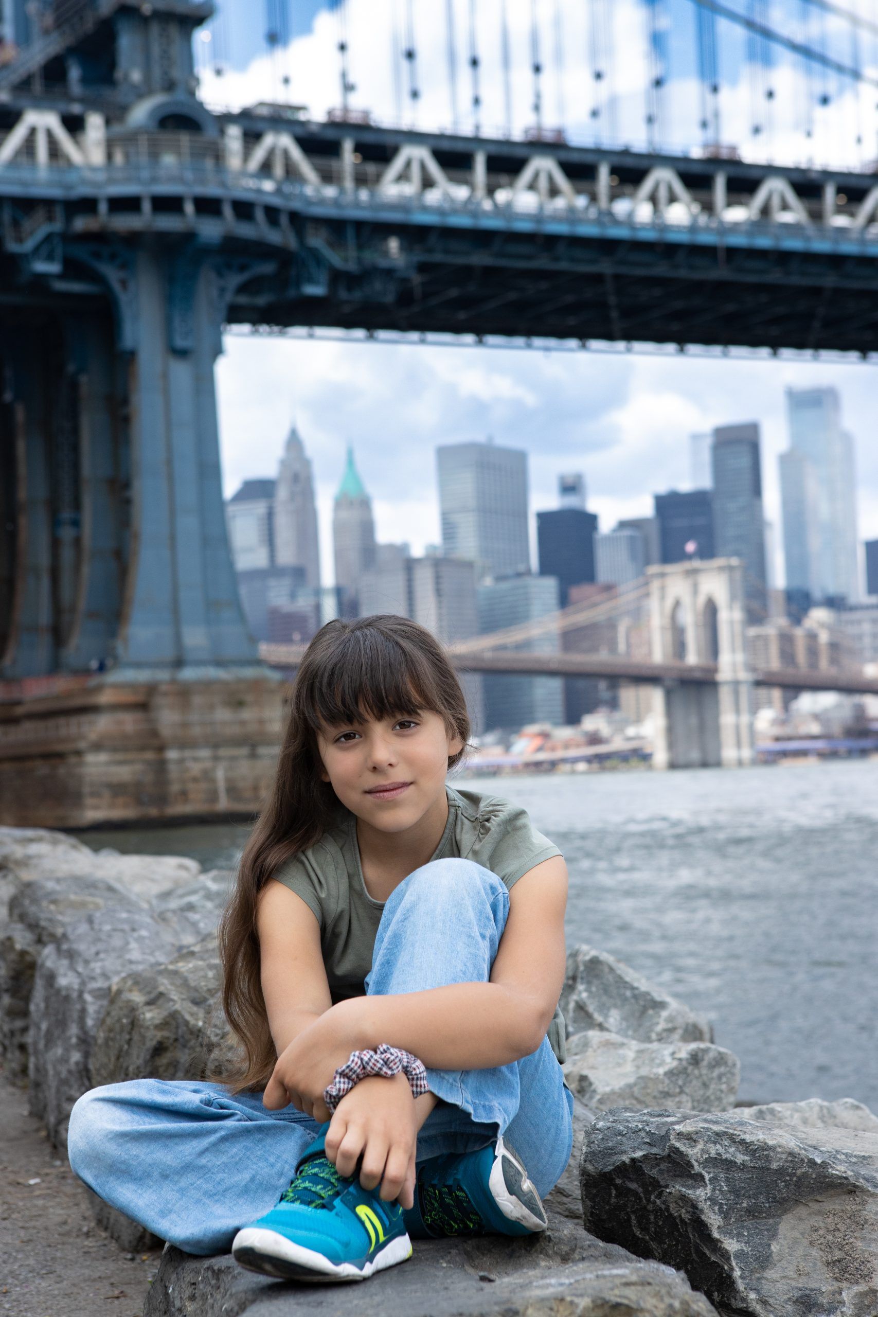 Petite fille posant pour une photo au pied du Manhattan Bridge à New York