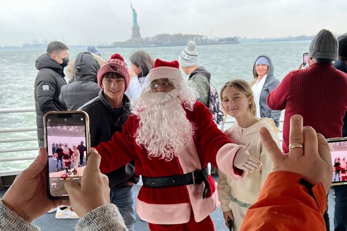 Touristes avec le père Noël devant la statue de la Liberté à New York